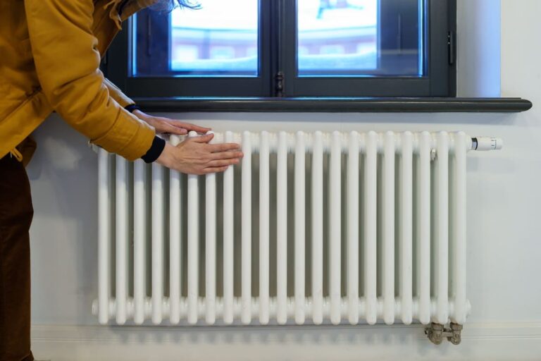 woman-warming-hands-near-heating-radiator-after-wi-2022-11-15-04-20-55-utc